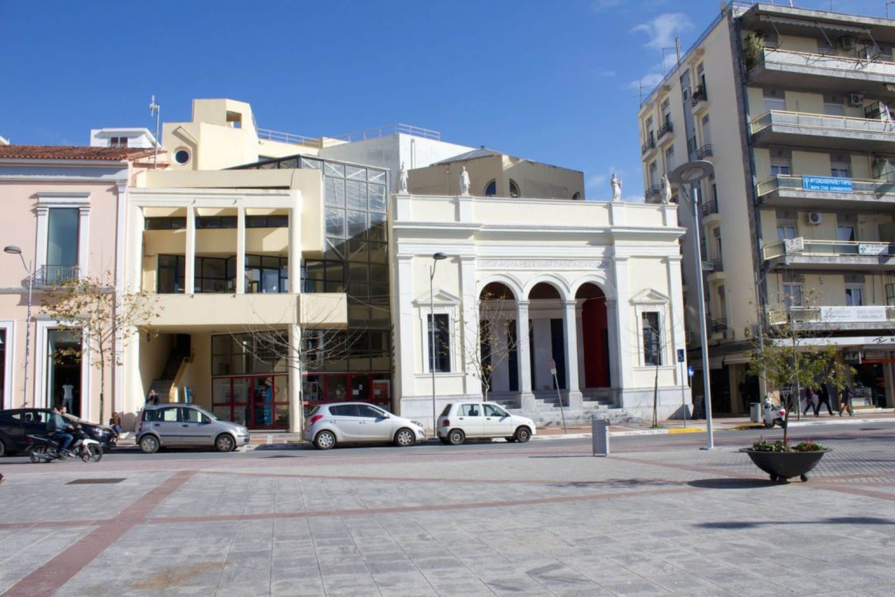 A building with a modern facade, a staircase leading to an upper level, and a large entrance with columns.