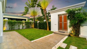 A modern house with a well-maintained lawn, a stone pathway, and a wooden door. - Luxury Pool Villa 608 (Pattaya)