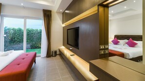 A modern hotel room with a large bed, a TV mounted on the wall, and a balcony with a view of greenery. - Luxury Pool Villa 608 (Pattaya)