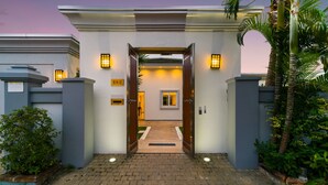 A gated entrance with a pathway leading to a building, a palm tree, and a sign with the number 608. - Luxury Pool Villa 608 (Pattaya)