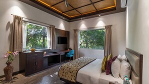 A hotel room with a bed, desk, and large windows. - Ramya Resort & Spa (Udaipur)