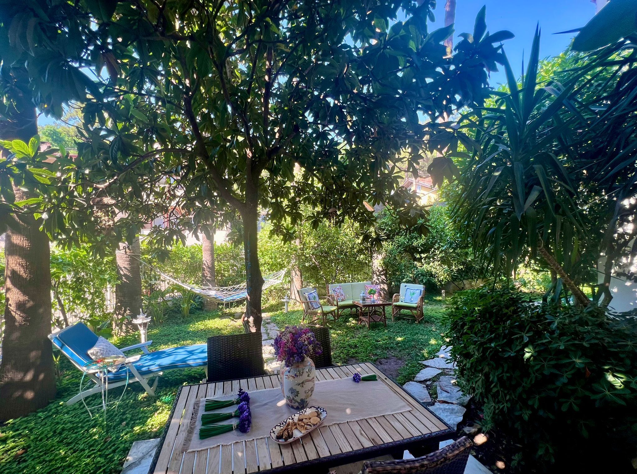 Un área de estar al aire libre con una mesa, sillas y una hamaca.