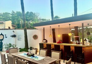 An outdoor dining area with a bar, wooden furniture, hanging plants, and a view of the surrounding trees. - Carikci Hotel - + 16 Adult"s Only  (Marmaris)