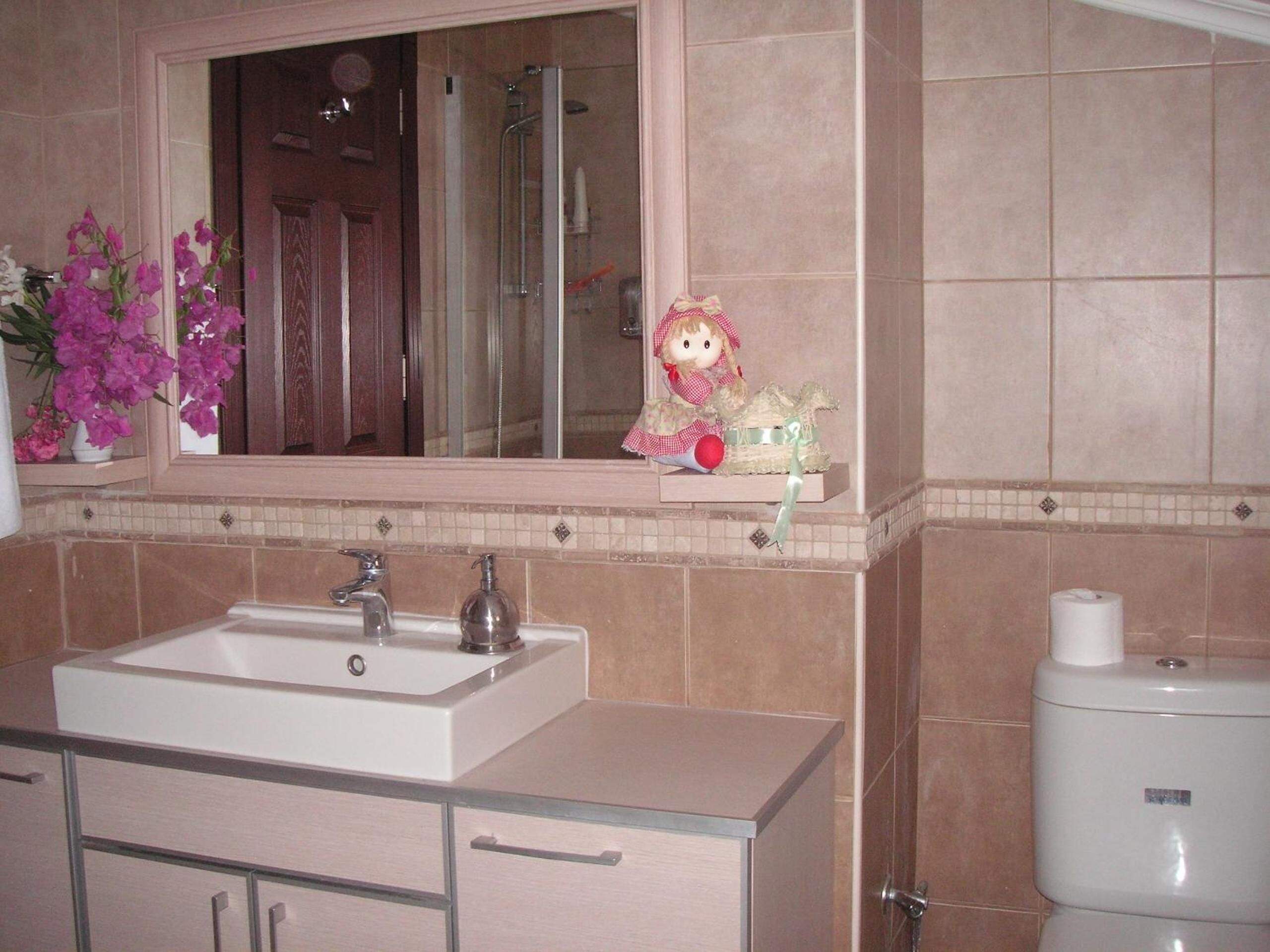 A bathroom with a white sink, a mirror above it, and a toilet.