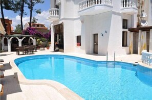 Una piscina al aire libre, sombrillas, tumbonas