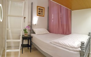 A bedroom with a bed, a bedside table with a lamp, a chair, and a door.