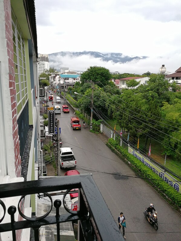 Une vue de rue avec des véhicules, un piéton et une montagne en arrière-plan.
