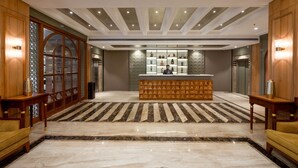A lobby with a reception desk, wooden paneling, and a patterned carpet. - Freesia By Express Inn (Mumbai)