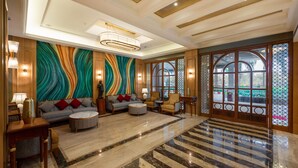 A spacious lobby with a marble floor, a large sofa set, and a colorful abstract mural on the wall. - Freesia By Express Inn (Mumbai)