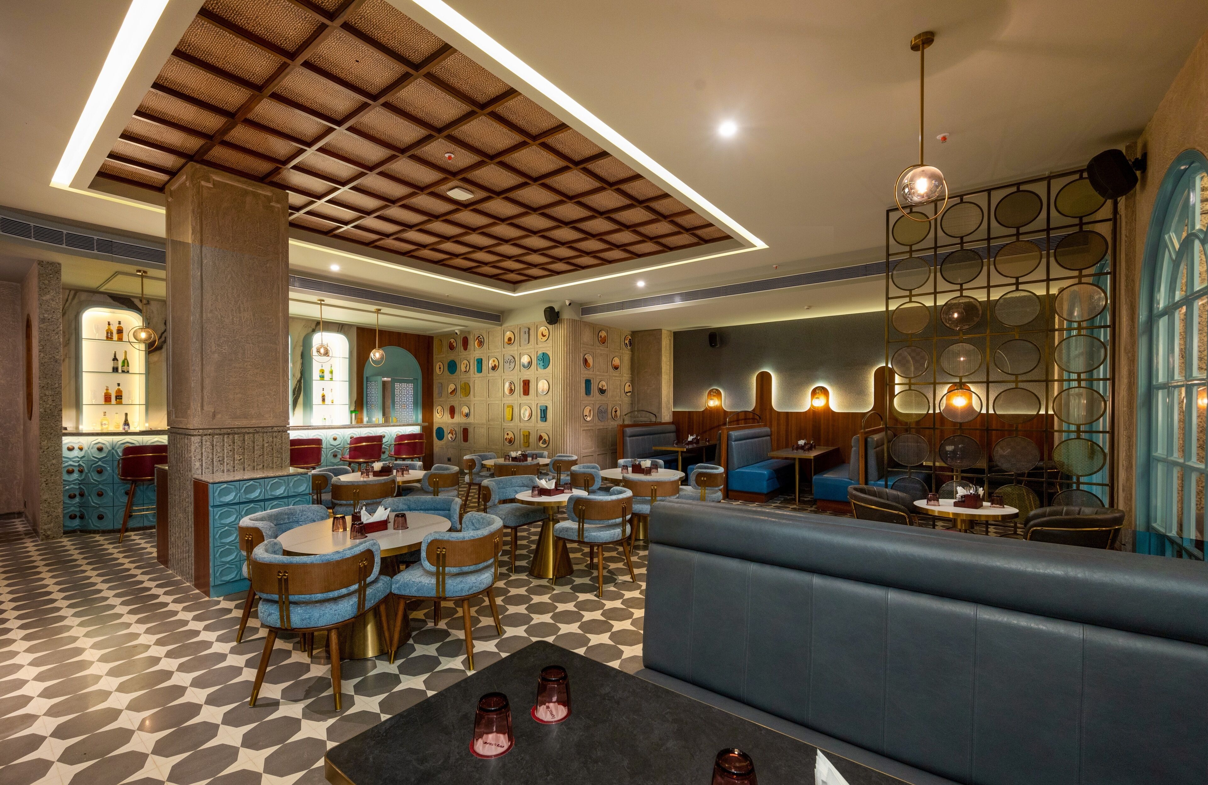 Un restaurante con piso a cuadros, mesas redondas y asientos tapizados en azul.