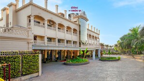 A hotel with a large central atrium, multiple balconies, and a well-maintained garden area. - Freesia By Express Inn (Mumbai)