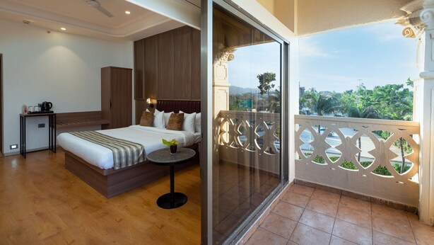 A hotel room with a bed, bedside table, and a balcony with a decorative railing. - Freesia By Express Inn (Mumbai)