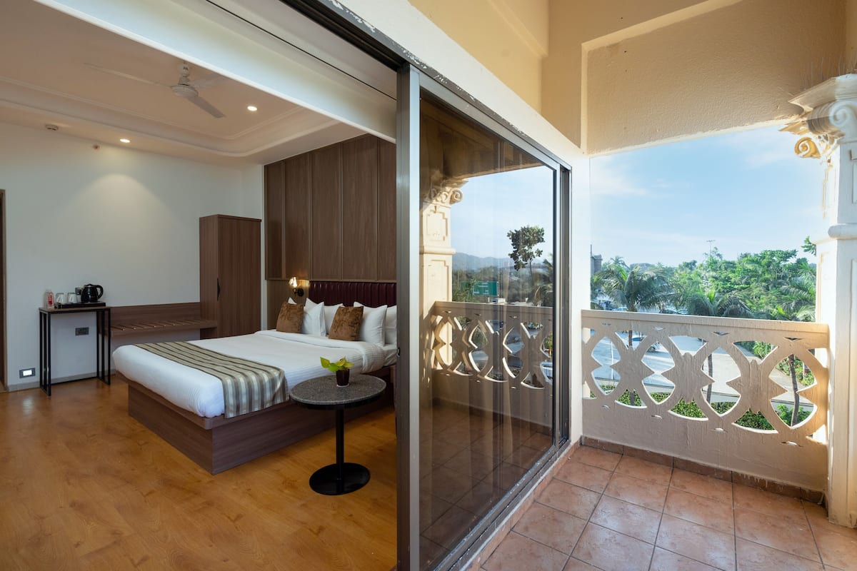 A hotel room with a bed, bedside table, and a balcony with a decorative railing.