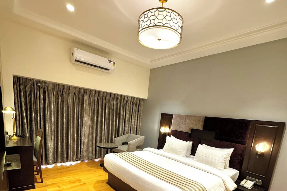 A modern hotel room with a large bed, a desk, and a chair.