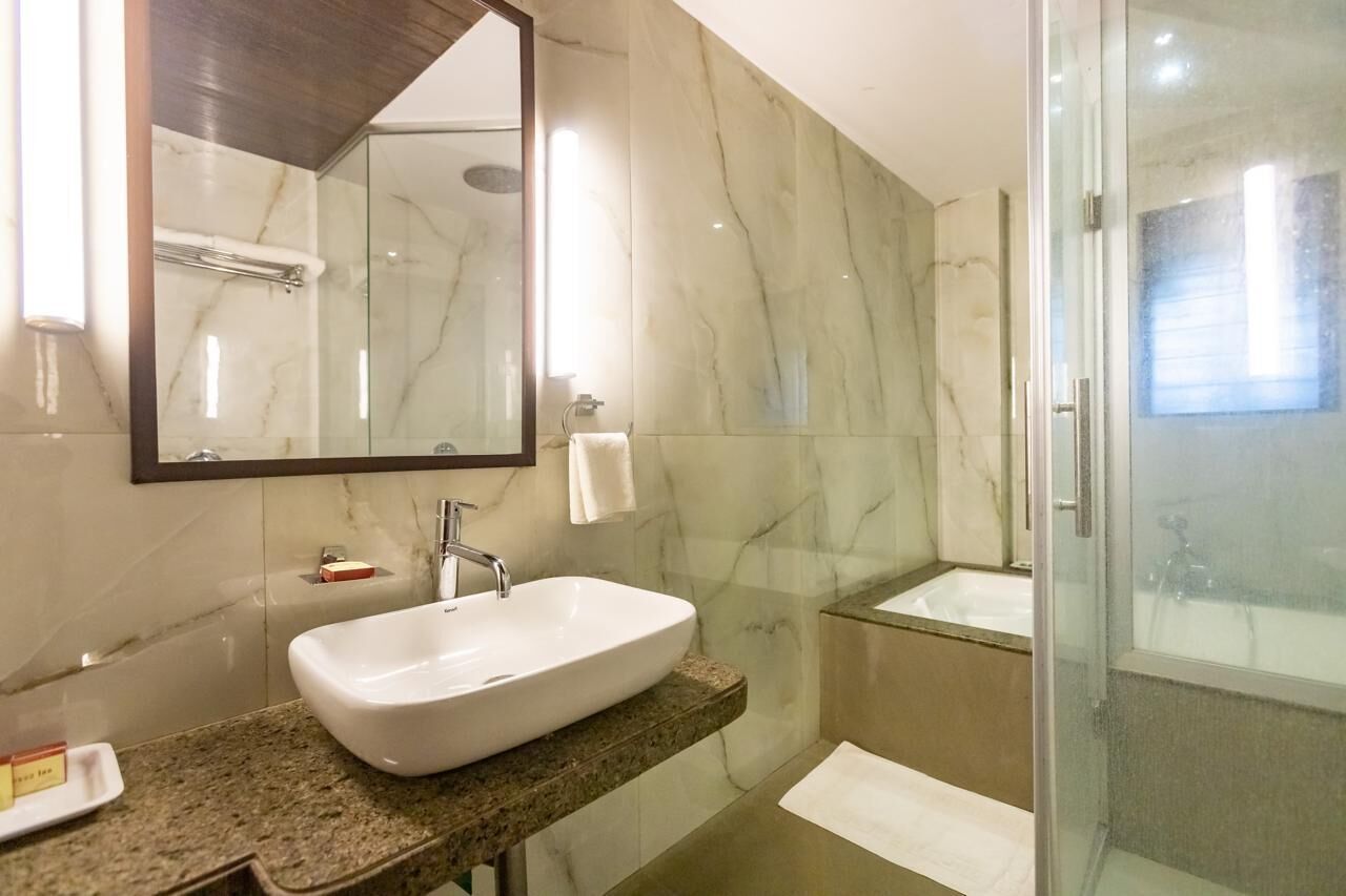 Een moderne badkamer met een marmeren wastafel, een grote spiegel, een douche met glazen wanden en een bad.
