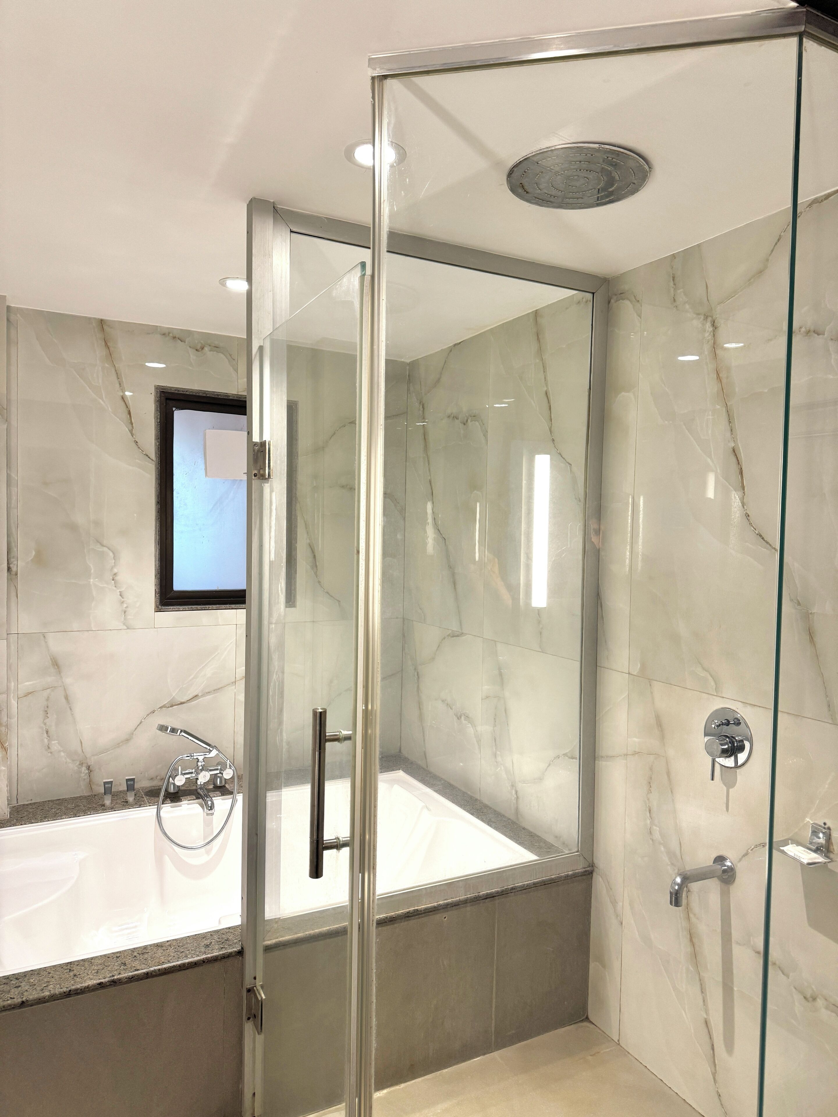 A modern bathroom with a glass-enclosed shower, a bathtub, and a toilet.