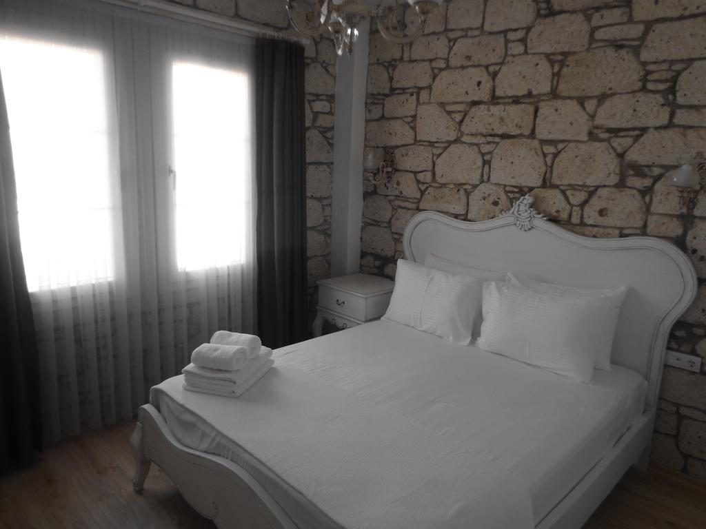 A bedroom with a stone wall, a white bed, and a nightstand.