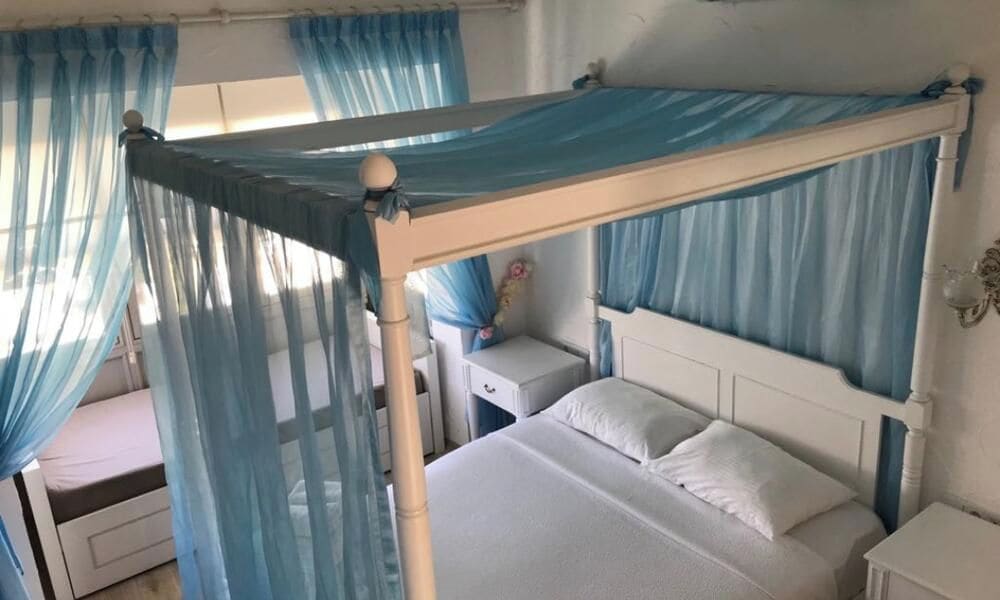 A bedroom with a canopy bed, a bedside table, and a nightstand.