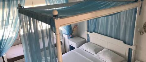 A bedroom with a canopy bed, a bedside table, and a nightstand.