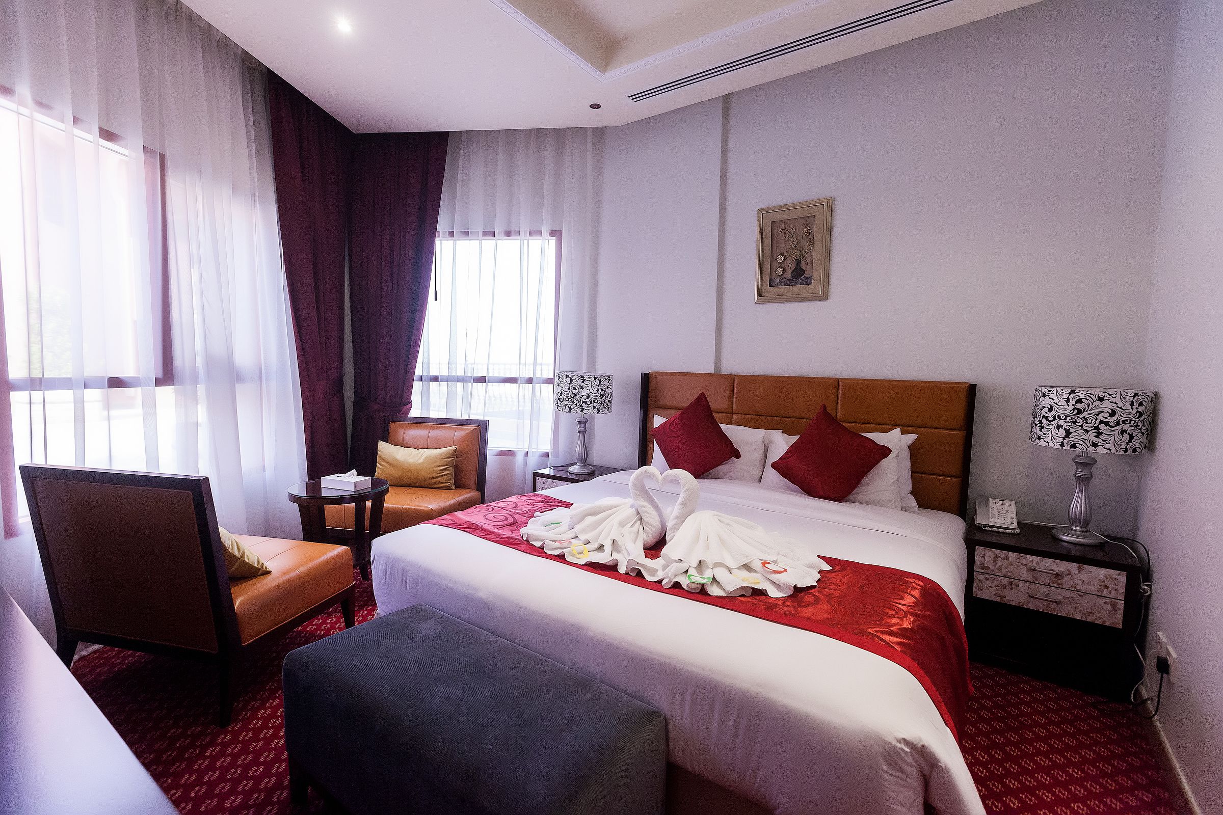 A hotel room with a large bed, a chair, a bedside table, and a nightstand.