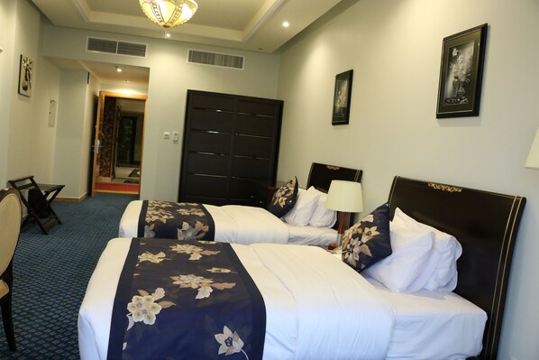 A hotel room with two beds, a desk, and a chair.