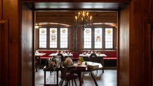 A restaurant interior with wooden walls, a chandelier, stained glass windows, and tables set for dining. - Hotel Zunfthaus zur Rebleuten (Chur)