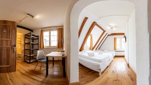 A modern loft bedroom with a wooden floor, a desk, a chair, and a bed. - Hotel Zunfthaus zur Rebleuten (Chur)