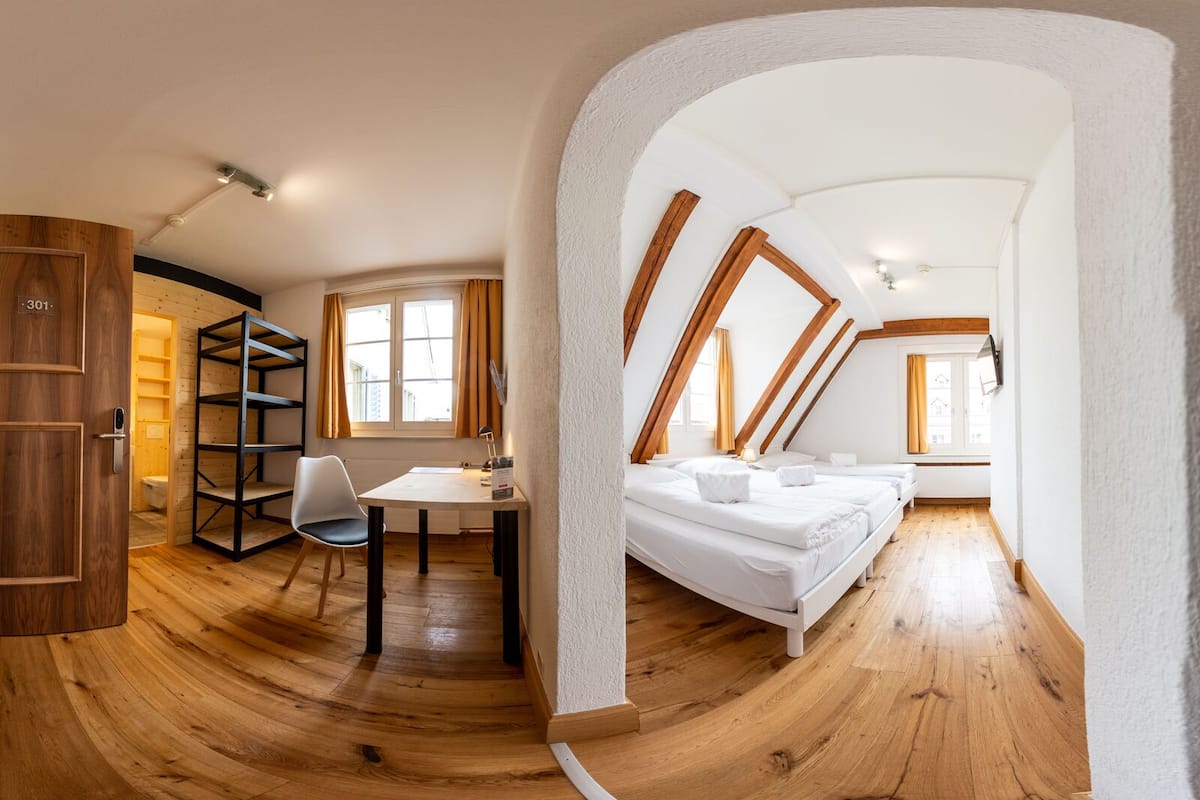 Een moderne loft slaapkamer met houten vloer, bureau, stoel en bed.