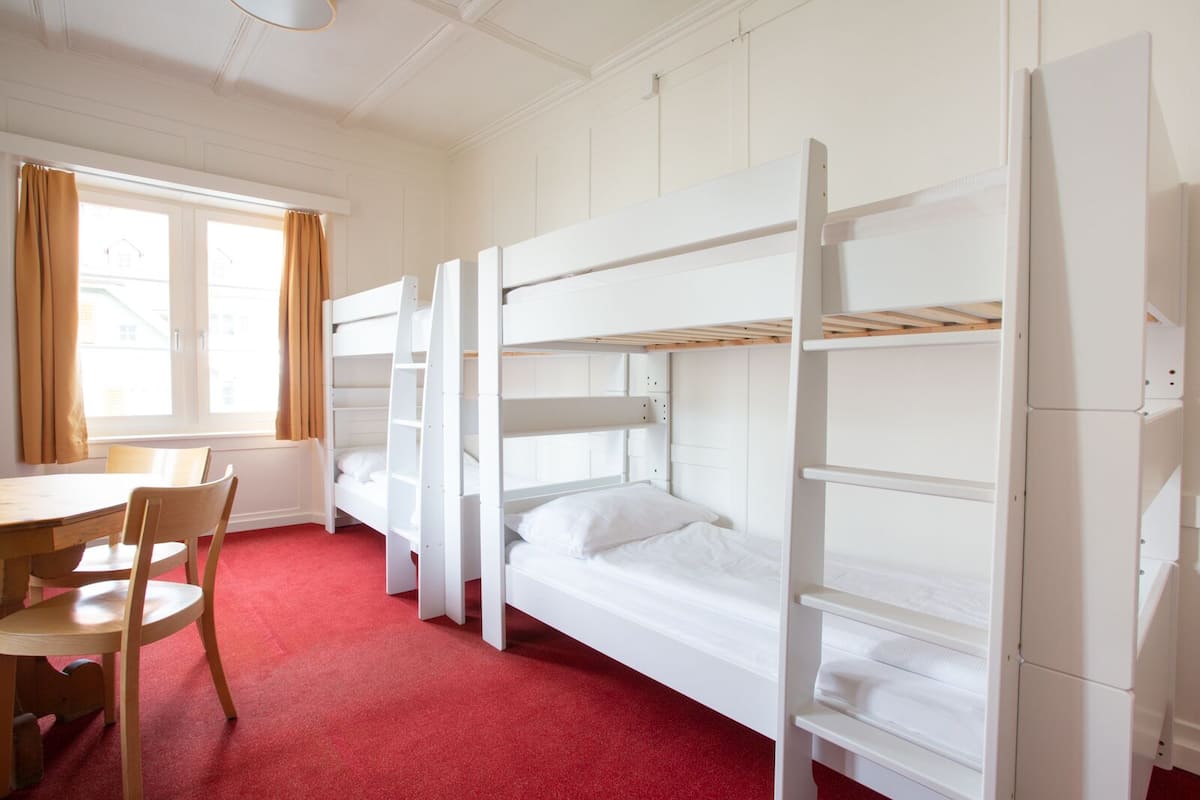 Een slaapzaal met stapelbedden, een bureau en een stoel.