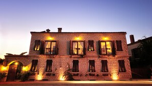 A stone building with multiple windows and balconies, illuminated by warm lighting. - Koclu Konagi Hotel (Cesme)