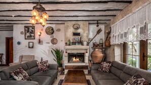 A cozy living room with a fireplace, two sofas, a coffee table, and a chandelier. - Koclu Konagi Hotel (Cesme)