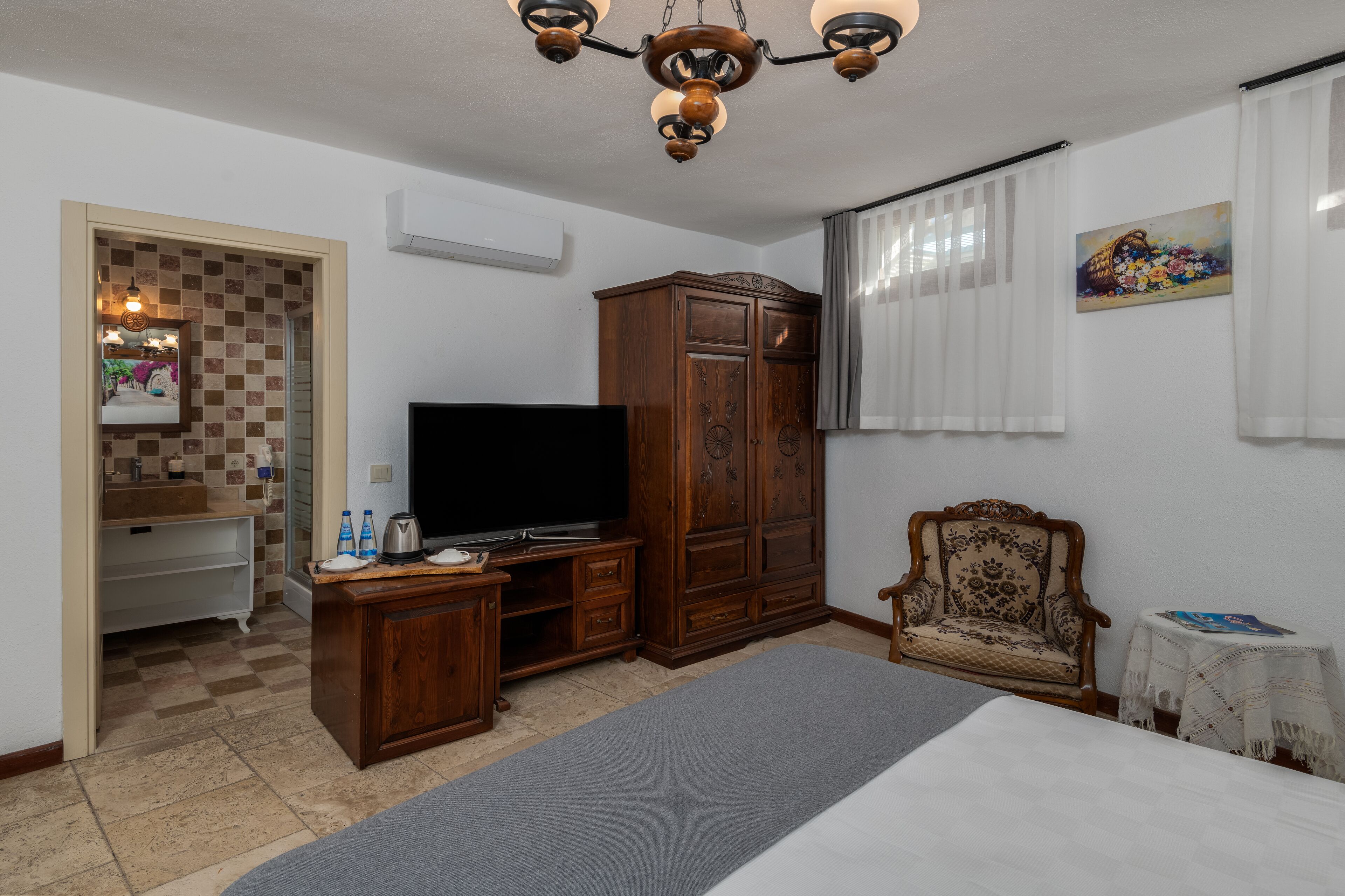 Een slaapkamer met een bed, een televisie, een houten kledingkast, een stoel en een klein tafeltje.