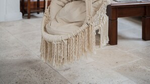 A macrame hanging chair in a room with a wooden table and a sofa. - Koclu Konagi Hotel (Cesme)