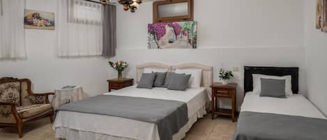 A bedroom with two beds, a chandelier, a chair, and artwork on the walls.