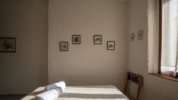 Un dormitorio con cama, ventana con cortina y varias fotografías enmarcadas en la pared.