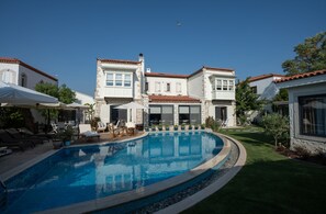 A pool surrounded by a well-maintained lawn and white buildings with red-tiled roofs. - Sedirli Ev Alacati (Cesme)