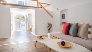 Uma sala de estar moderna com escada, paredes brancas e piso de madeira.