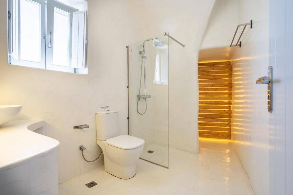 Een moderne badkamer met een glazen douchecabine, een wit toilet en een wandpaneel van houten latten.