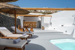 A sunlit outdoor pool area with lounge chairs and a wooden pergola. - Karpimo Suites (Santorini)