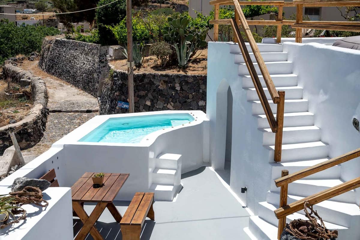 A rooftop pool area with a wooden staircase and a small table.