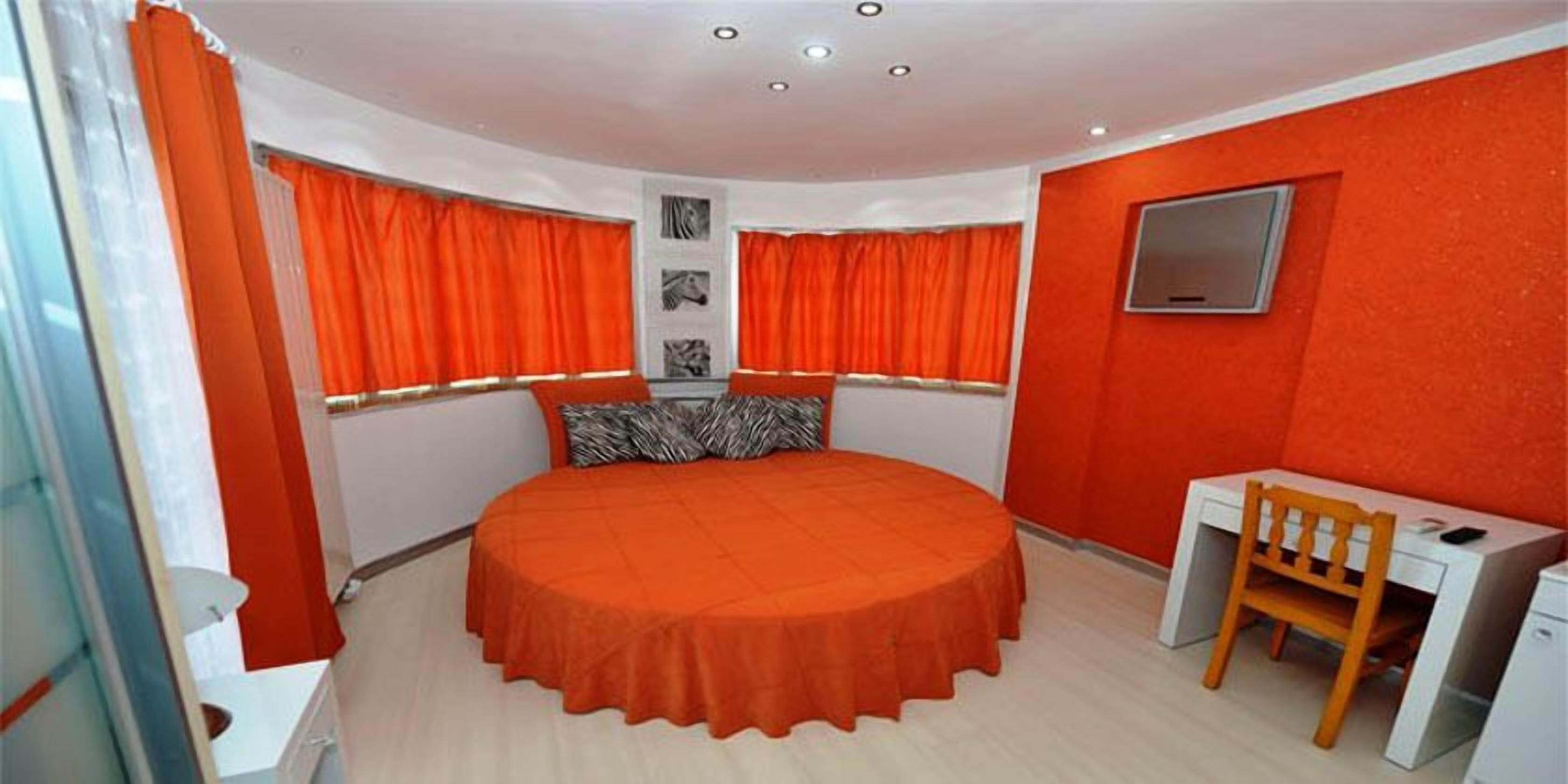 Een slaapkamer met een rond bed, een bureau en een stoel.