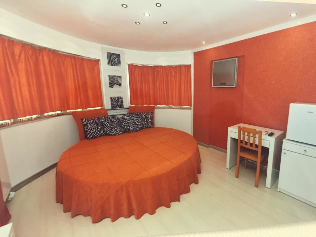 Un dormitorio con cama redonda, un escritorio y una silla.
