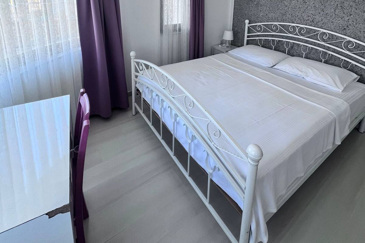 A bedroom with a bed, curtains, an air conditioning unit, and a window.