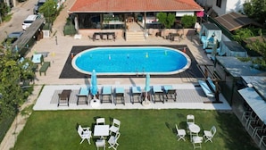 Un edificio residencial con piscina, mobiliario exterior y vistas del barrio circundante.