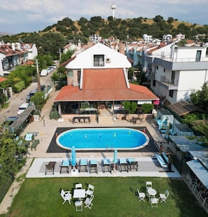 A residential building with a swimming pool, outdoor seating, and a view of the surrounding neighborhood. - Dardanos Pansiyon (Çanakkale)