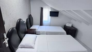 A room with two beds, a TV, a window with curtains, and a door.