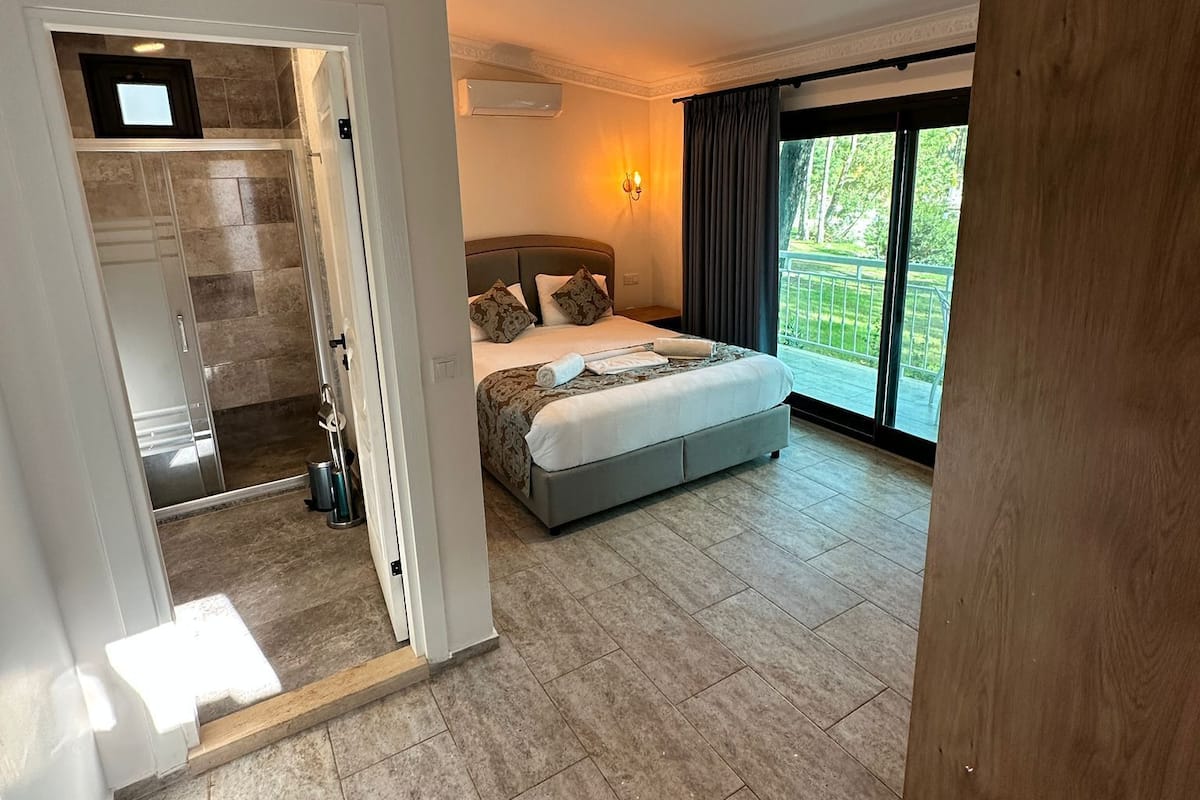 A spacious bedroom with a large bed, a walk-in closet, and a sliding glass door leading to a balcony.
