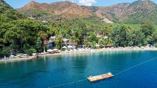 A coastal area with a dock, boats, and a beach with umbrellas and sun loungers. - Joya Del Mar Hotel (Marmaris)