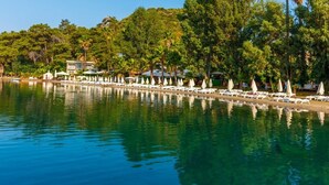 A beachfront hotel with a poolside area, lounge chairs, and umbrellas. - Joya Del Mar Hotel (Marmaris)