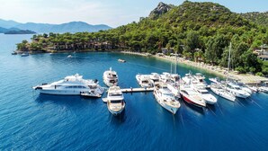 A marina with several yachts docked, surrounded by lush greenery and mountains in the background. - Joya Del Mar Hotel (Marmaris)